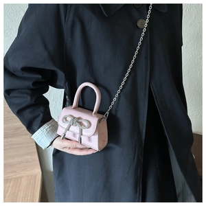 Close-up of pink mini crossbody bag with a sparkling rhinestone bow and silver chain