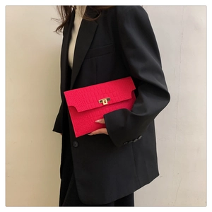Detail of bright pink crocodile embossed envelope clutch bag with gold rectangular clasp