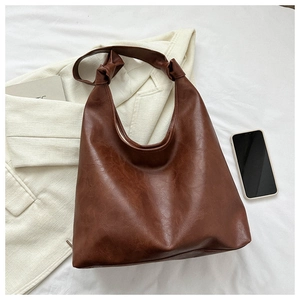 Close-up of a vintage brown PU leather tote bag with unique knot shoulder strap details