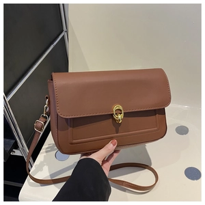 Détail du sac à bandoulière marron avec boucle dorée imbriquée et finition en cuir mat