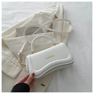 Detail of white PU leather handbag with gold fashion lettering and thin strap