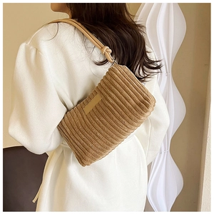 Detailed view of khaki corduroy shoulder bag with vertical stripe texture on a model