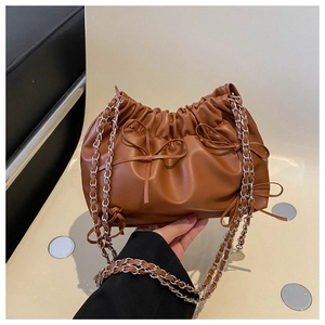 Detail of brown pleated cloud bag with leather bow and metallic silver chain strap