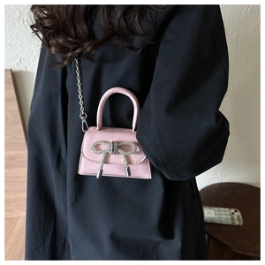 Detail of a pink mini crossbody bag featuring a large silver rhinestone bow ornament