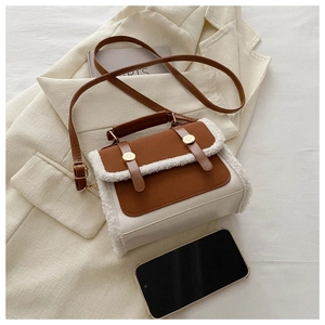 Detail of color-block crossbody bag featuring brown leather trim and white faux fur edges