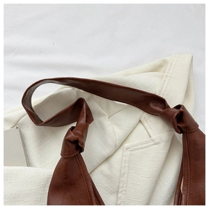 Detail shot of brown PU leather shoulder bag featuring a unique knotted strap design