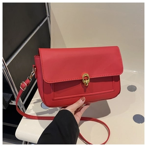 Détail du sac bandoulière rouge avec fermoir doré et texture en cuir raffiné