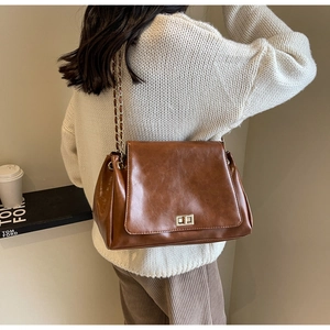 Detailed view of brown vintage leather crossbody bag with gold metal twist lock and chain strap