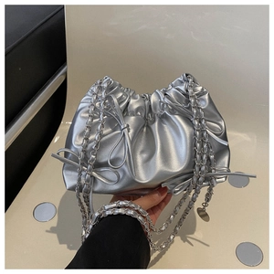 Close-up of metallic silver pleated cloud bag with bow detail and chain strap