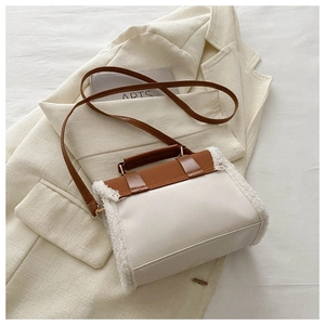Detail of cream crossbody bag with brown leather flap and white faux shearling side panel