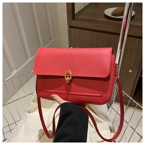 Détail d'un sac bandoulière rouge en cuir avec une boucle dorée circulaire élégante