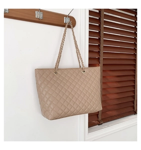 Dettaglio della borsa tote beige trapuntata con cuciture a rombi e tracolla a catena