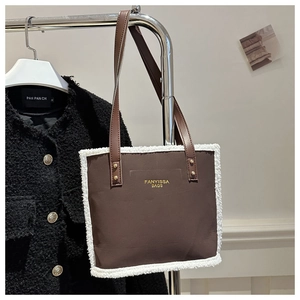 Detail of brown matte tote bag with plush faux fur trim and gold letter branding