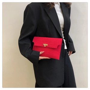 Detail of red crocodile texture envelope clutch bag with gold rectangular turn-lock