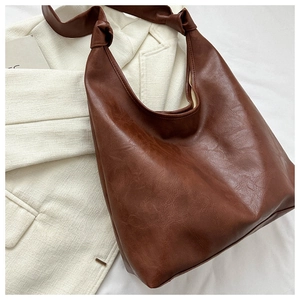 Macro detail of dark brown hobo bag showing soft vintage leather texture and knotted strap