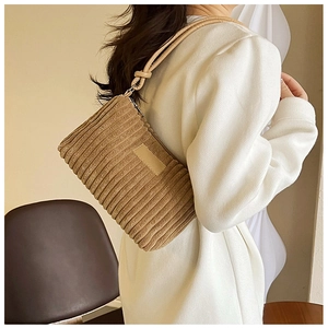 Detail of khaki corduroy hobo bag featuring vertical pleated texture and knotted leather strap