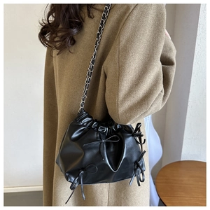 Close-up of black bucket bag featuring pleated clouds design and bow-knot details