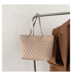 Dettaglio della borsa shopper trapuntata beige con catena dorata e motivo a rombi