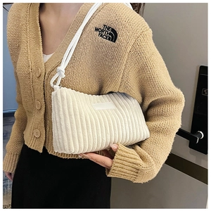 Detailed texture of off-white corduroy shoulder bag with rope straps and minimalist label