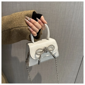White mini crossbody bag with a sparkling rhinestone bow and silver chain strap