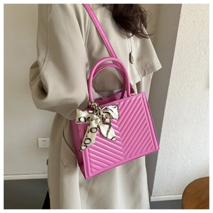 Bright pink V-quilted tote bag with decorative silk scarf handle on stylish model