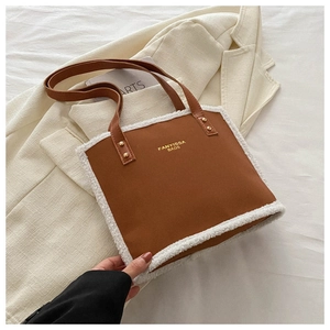 Detail of brown faux leather tote bag featuring white shearling trim and gold rivets