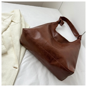 Detailed view of dark brown hobo bag with vintage leather texture and knot shoulder strap