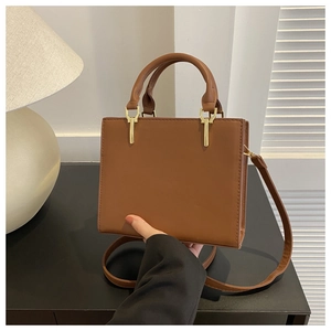 Detail of brown faux leather handbag with golden hardware and adjustable shoulder strap