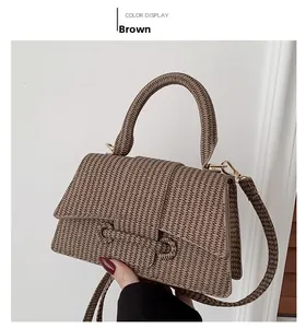 Close-up of brown textured crossbody bag with gold buckle and adjustable strap