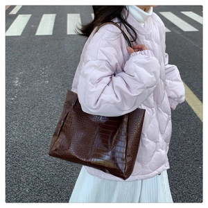 Detail der dunkelbraunen Totebag mit Kroko-Prägung und Vintage-Textur vor Straßenkulisse