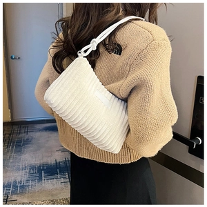 Detailed texture of a white corduroy shoulder bag with soft vertical stripes and knot strap