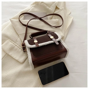 Close-up of vintage brown crossbody bag with faux shearling trim on a blazer