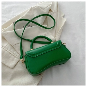 Detail of vibrant green hourglass bag with gold hardware on white blazer and magazine