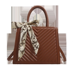 Sac à main marron vintage avec matelassage en V et foulard sur fond blanc