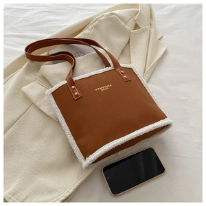 Close-up of brown tote bag with white faux shearling trim and golden logo detail
