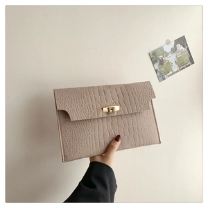 Close-up of beige crocodile texture envelope clutch with gold metal twist lock closure