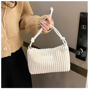 Detail of warm white corduroy handbag featuring a knotted strap and ribbed texture