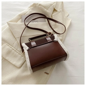 Detail of retro dark brown leather crossbody bag with white faux fur trim and gold buckle