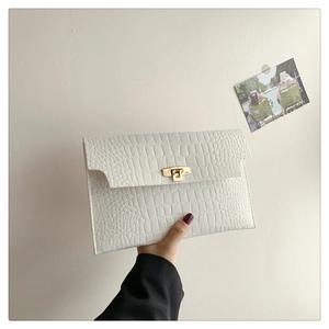 Detailed shot of white crocodile texture envelope clutch with gold rectangular clasp