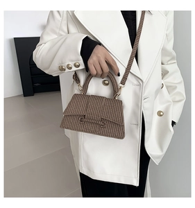 Detailed view of brown woven texture on a trapezoid handbag with gold hardware