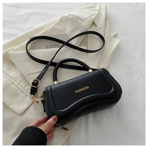 Detail of black PU leather handbag with gold 'FASHION' text on white suit background