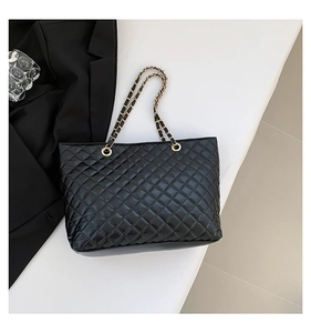 Dettaglio borsa shopper trapuntata nera in pelle con catena dorata su piedistallo bianco