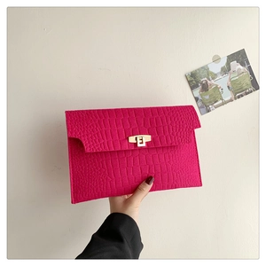 Detail of rose pink felt envelope clutch with crocodile texture and gold buckle
