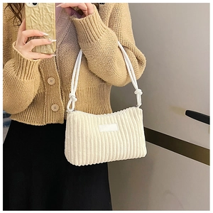 Close-up of white corduroy shoulder bag showing vertical rib texture on casual outfit