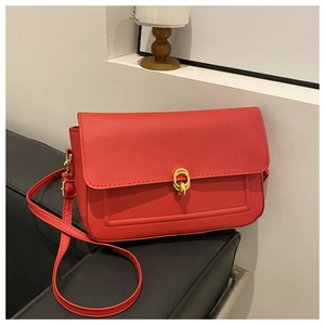 Détail d'un sac carré rouge avec boucle dorée ronde et coutures de précision