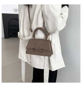 Detail view of the brown woven texture and curved handle on the urban minimalist handbag