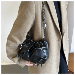 Detail of black pleated cloud bucket bag with bow accents and silver chain strap