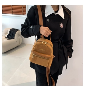 Close-up of brown velvet backpack featuring golden zippers and fashion brand metal tag
