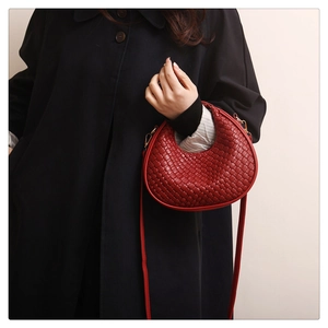 Dettaglio della borsa a mezzaluna in pelle intrecciata rossa con finiture dorate