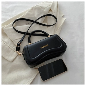 Detail view of black PU leather handbag with gold lettering next to a smartphone